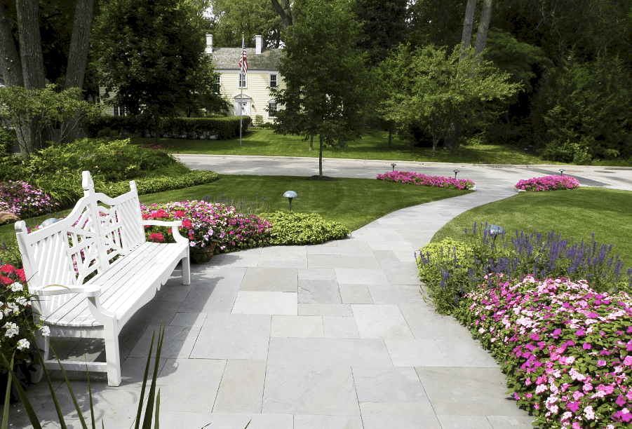 bluestone walkway with white bench bluestone walkway surrounded by push beds of annual flowers