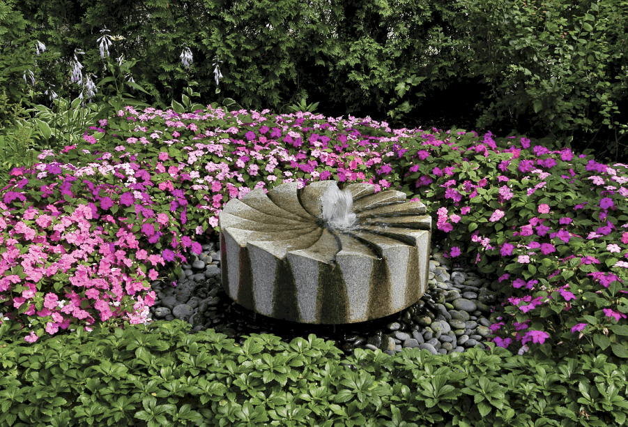 fountain made of granite millstone granite millstone fountain with Mexican blue pebbles and large bed of impatiens