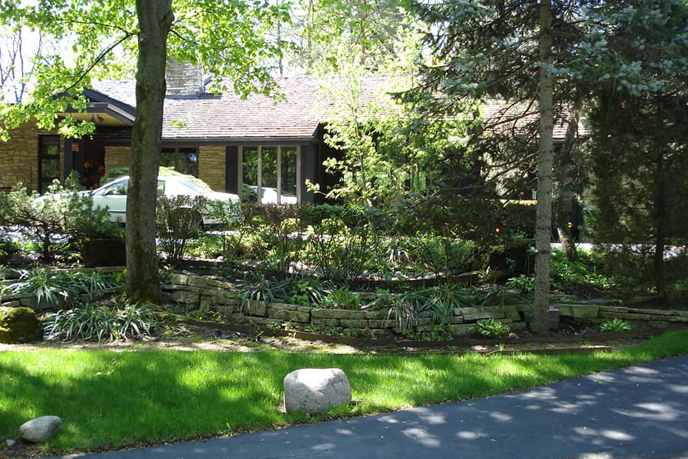 northbrook-retaining-wall-before As with many shady areas, the beds bordering this home's driveway featured expected foliage plants.
